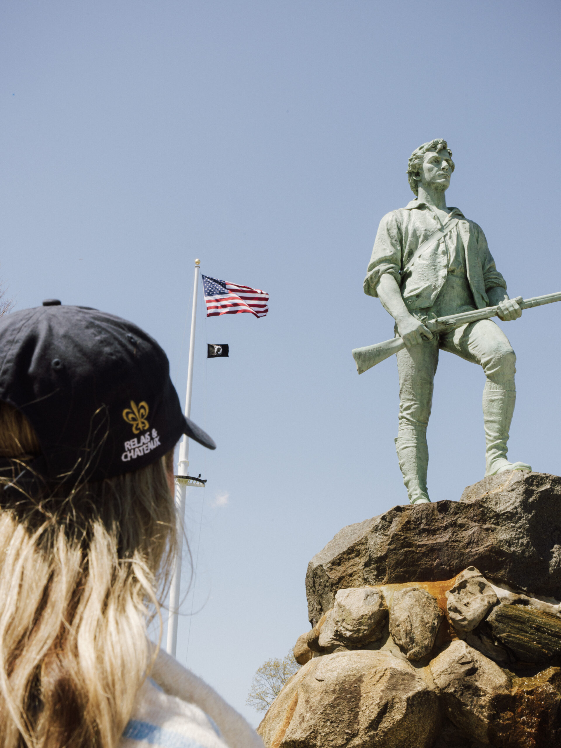 Woman staring at a minuteman statue with a usa flag