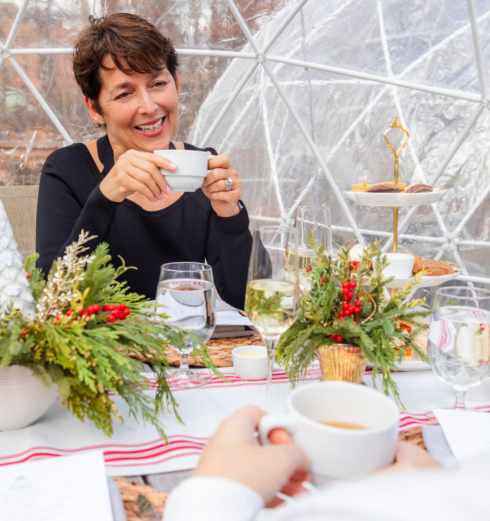 woman sitting in an igloo with a beverage