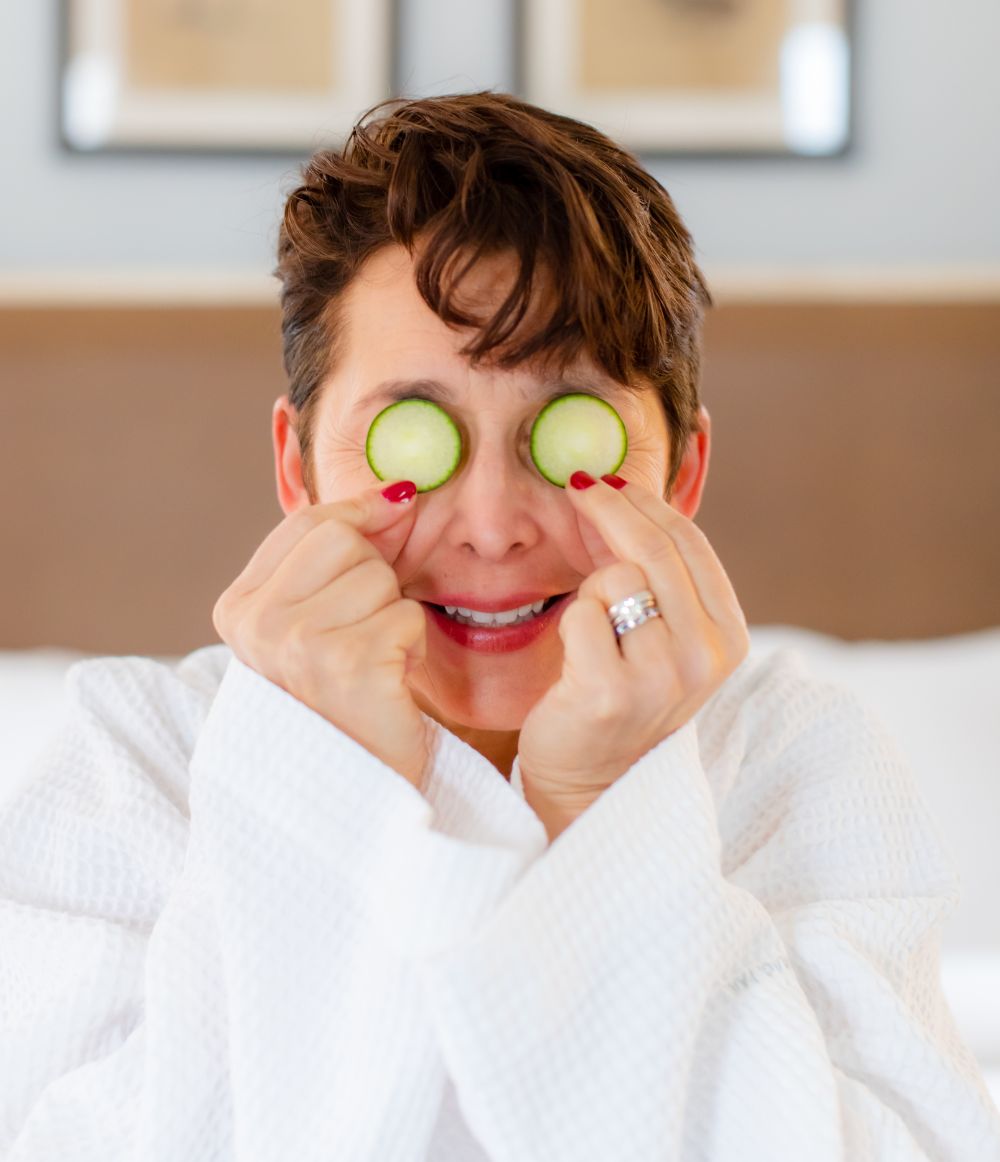 Person holding cucumbers on their eyes